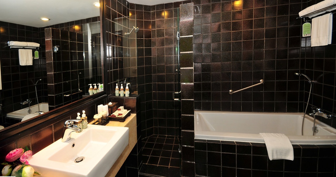 Elegante hotelbadkamer met donkere mozaïektegels, een witte waskom en sfeervolle verlichting die een spa-gevoel creëert.